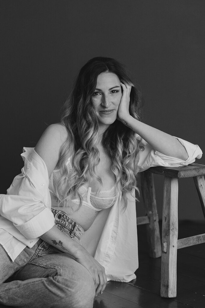 Frau sitzt auf dem Boden und lächelt bei ihrem Boudoirfotoshooting